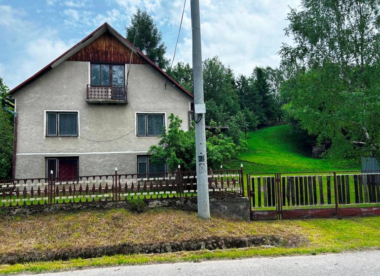 A family house in Veľká Lesná with a landscaped garden and lawn, surrounded by trees.