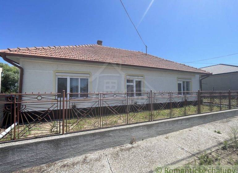 A family house in Nové Zámky with a sloped roof and a wrought iron fence.