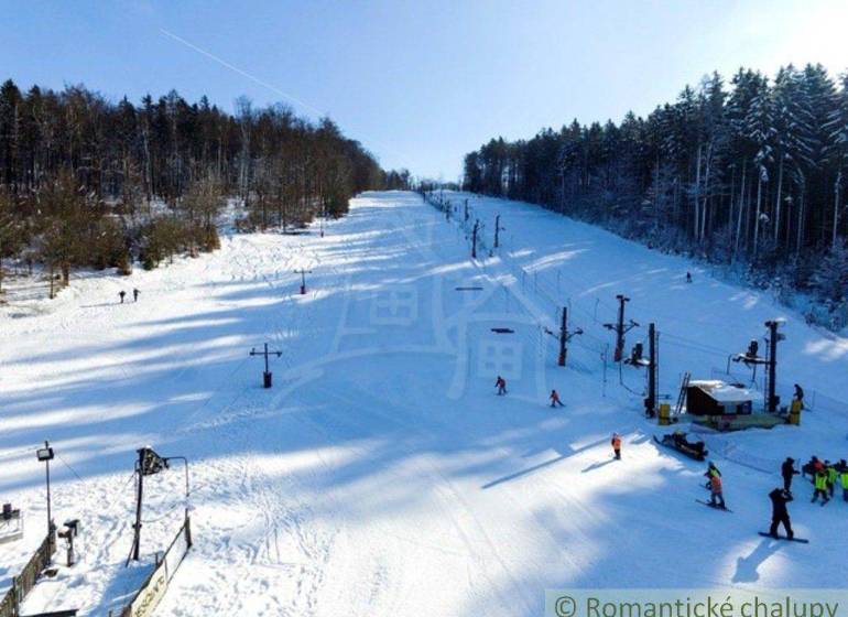 A snowy slope with a ski lift surrounded by forests in Stará Myjava.