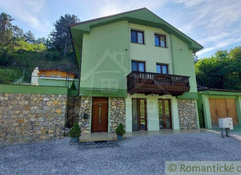 A family house in Dobrá Voda with stone details and a wooden balcony in a natural setting.