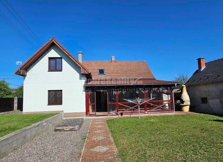 A family house in Malá Lehota with a veranda and a garden under the blue sky.