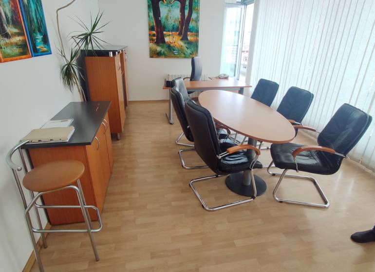 Offices with a round table and chairs, a painting hangs on the wall.