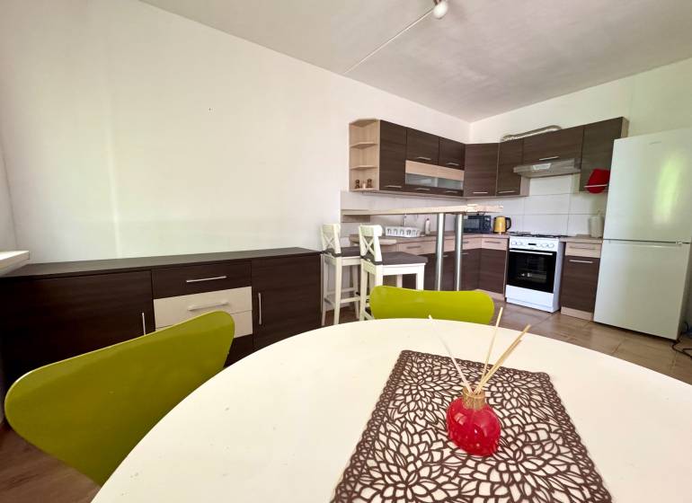A kitchen with a stove and a dining table in a 3-room apartment.