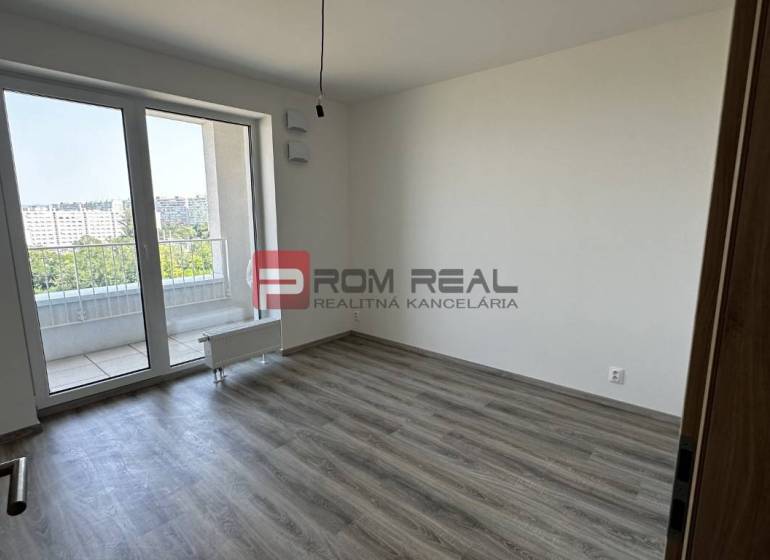 An empty room with laminate flooring and glass doors in a two-room apartment.