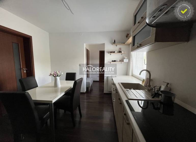 A furnished kitchen and a dining table with black chairs in a family house.
