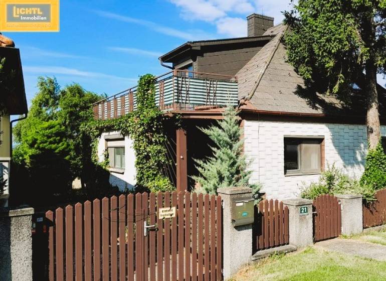 A family house in Hundsheim with a wooden fence, terrace, and abundant greenery.
