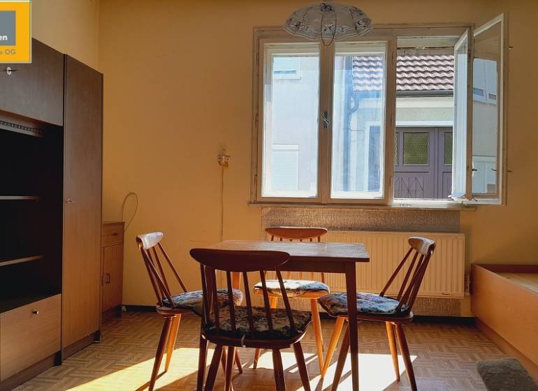 A room with a table and chairs lit by the sun, Apartment construction.