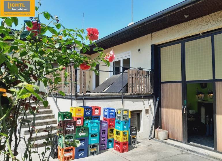 Flower-filled gastro spaces in Grossinzersdorf, with colorful crates in the yard next to the building.