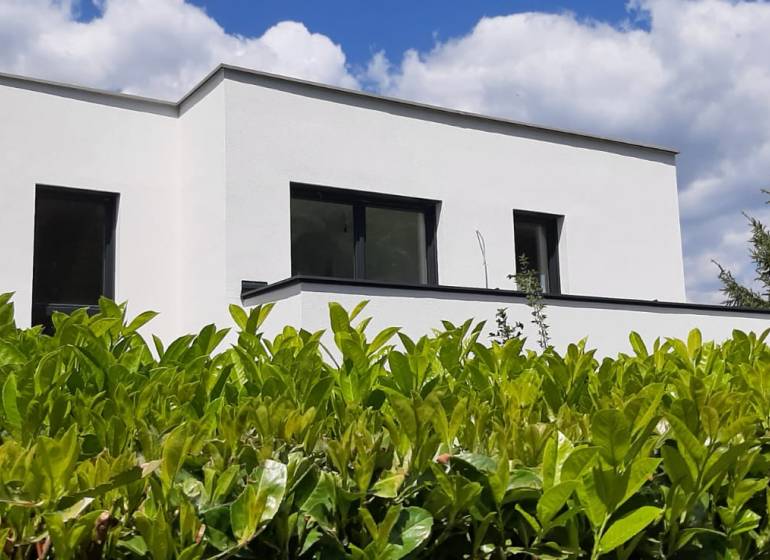 A villa in Hainburg an der Donau with a white facade, surrounded by greenery under a blue sky.
