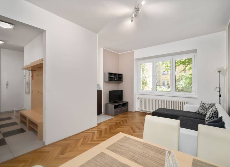 Living room with a sofa, dining table, and hallway in a 3-bedroom apartment.