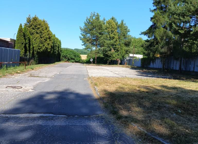 An asphalt road surrounded by trees and greenery in Prievidza, suitable for residential plots.