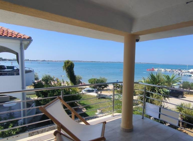 View from a family house in Vrsi of the sea and harbor with greenery.