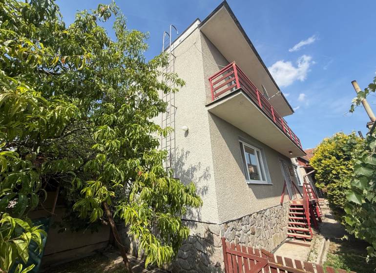 Rodinný dom v Skačanoch s balkónom, schodiskom a zeleňou v záhrade.