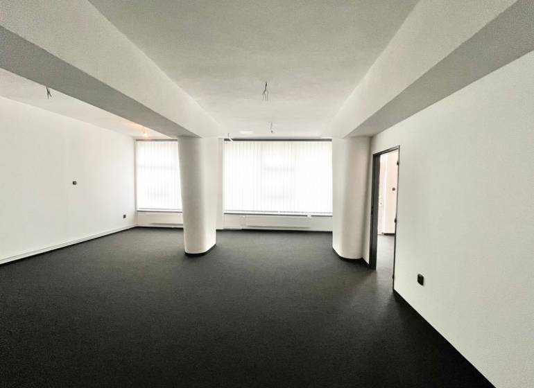 Spacious commercial premises with black carpet and white walls, unfurnished.
