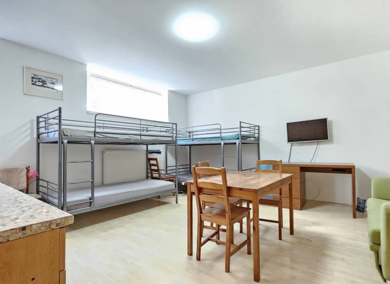 A room in a one-room apartment with bunk beds, a table, and a television.