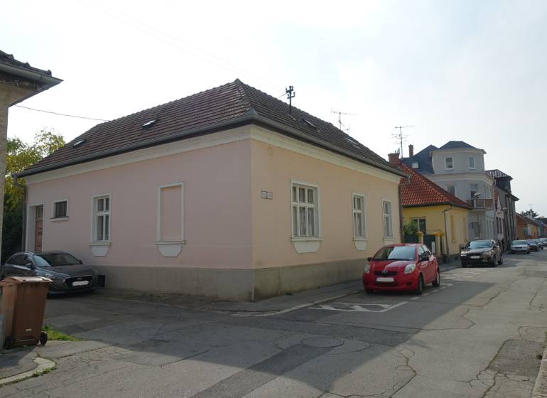 A family house on Hviezdoslavova Street in Piešťany. Pink plaster, cars parked next to it.