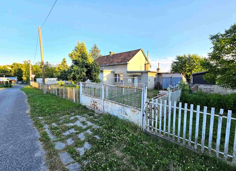 A family house in Kuzmice with a fence and a garden, next to a quiet street.