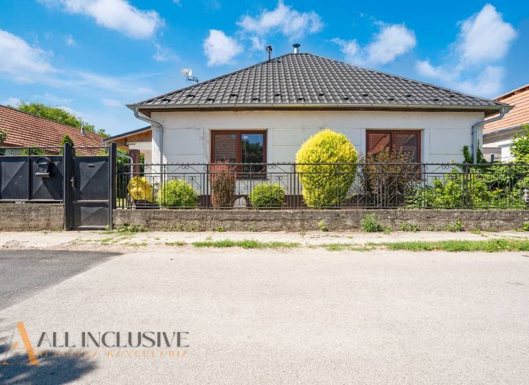 A family house in Tvrdošovce with a modern roof, landscaped garden, and wrought iron fence.