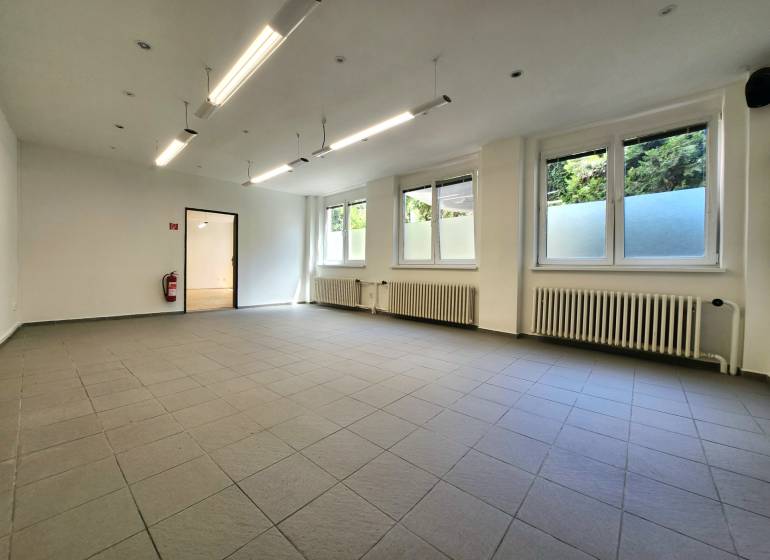 Spacious commercial spaces with windows, radiators, and pendant lighting.