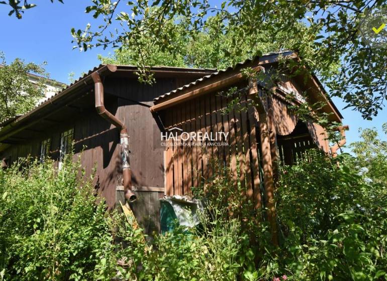 A wooden cottage in the Gardens in Nová Baňa surrounded by dense vegetation and greenery.