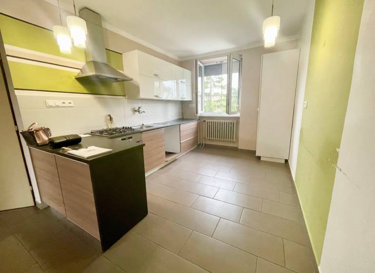 A kitchen in a 3-room apartment with a stove, a hood, and an open window.