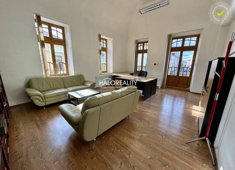 Offices with wooden floors, leather sofas, and large windows.