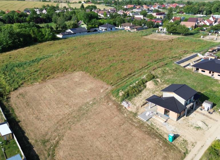 Construction of houses on Krátka Street in Alekšince with unfinished buildings and surrounding nature.