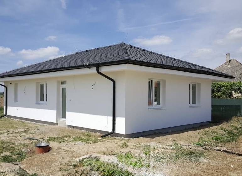 A family house in Western Slovakia with a white facade and a black roof.