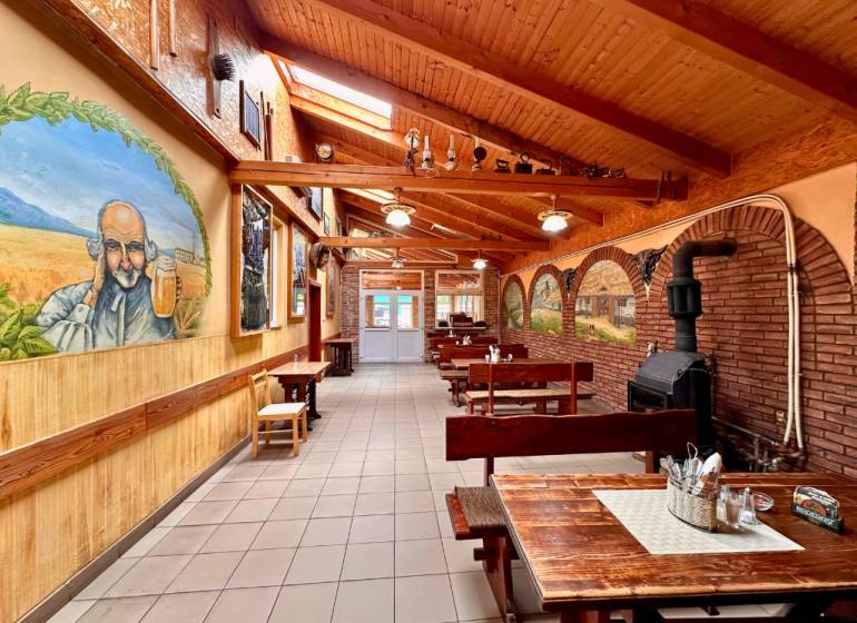 Interior of dining spaces with wooden benches, decorative paintings, and a brick fireplace.