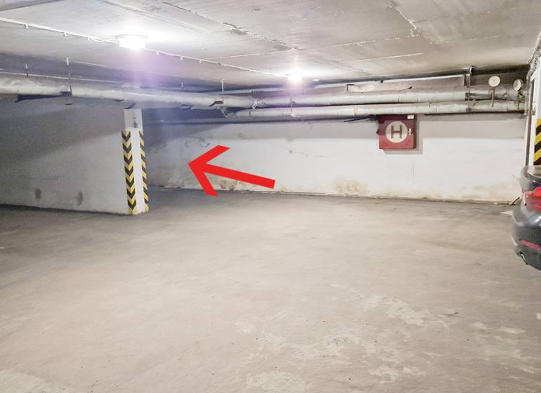 Underground parking area in the garage with a parking space by the wall and cars.