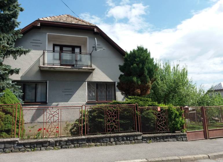A family house in Banská Bystrica with a balcony, front garden, and fencing.
