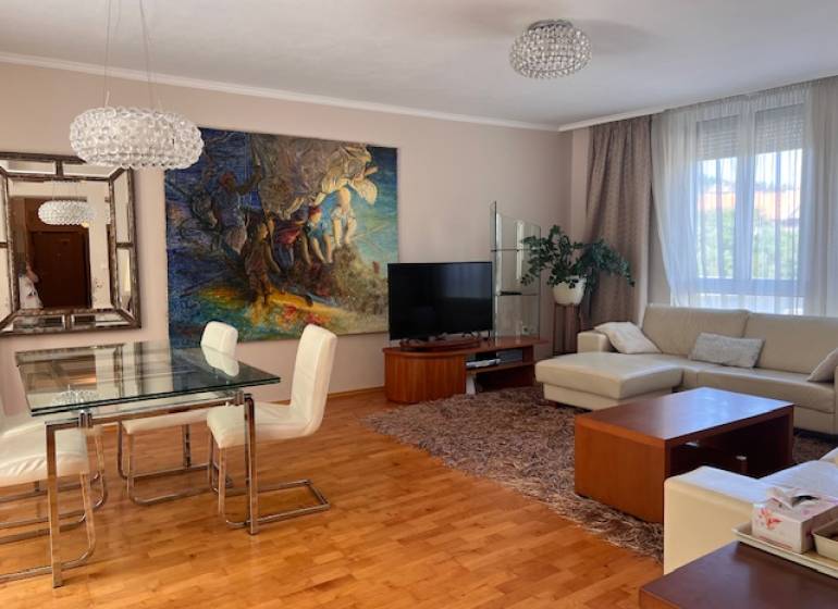Living room in a 3-room apartment with a sofa, dining table, and a painting on the wall.