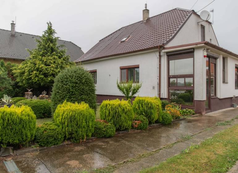 A family house in Rovinka surrounded by a landscaped garden with lush vegetation.