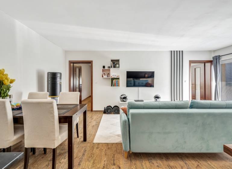 Living room in a 3-room apartment with a sofa, dining table, and a TV on the wall.
