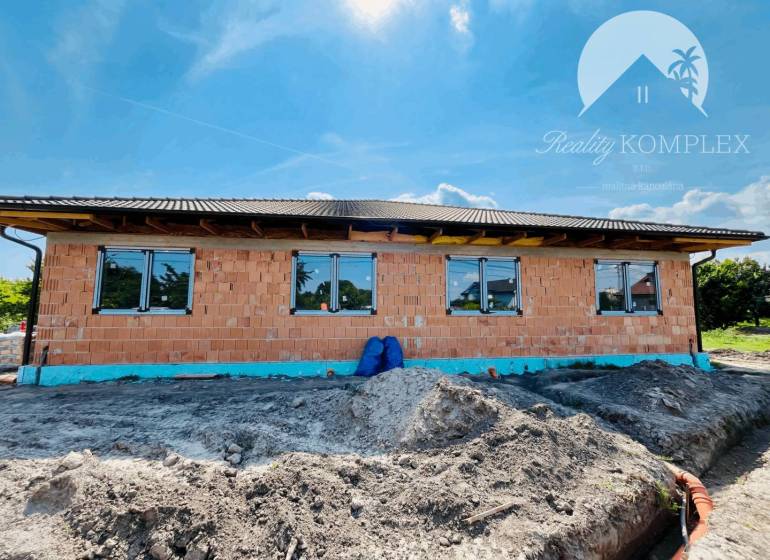 A family house under construction in Veľký Meder with brick walls and a roof.