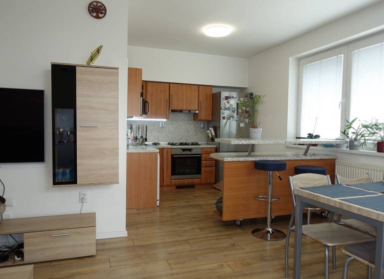 A kitchen with a bar counter and a dining table in a 3-room apartment.