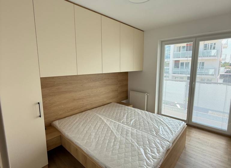 Bedroom in a 3-room apartment with a bed, wardrobe, and large window.