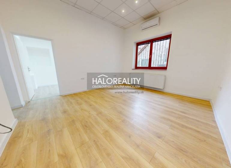 A bright room with laminate flooring and a large window in office spaces.