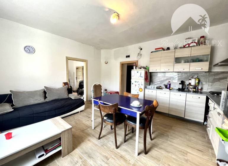 Living room with kitchen in a family house, comfortable sofa, wooden table, white sideboard.