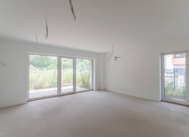 Bright empty room with large windows in a 2-room apartment.