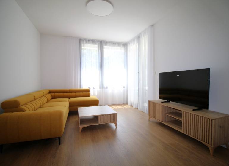 Living room with a large yellow sofa and a television in a two-room apartment.