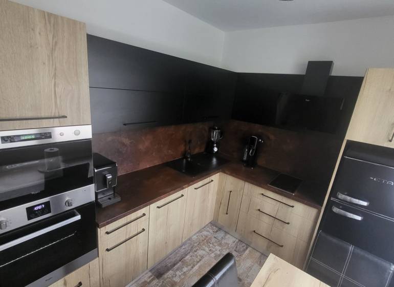 A kitchen in a studio apartment with wooden cabinets and modern appliances.