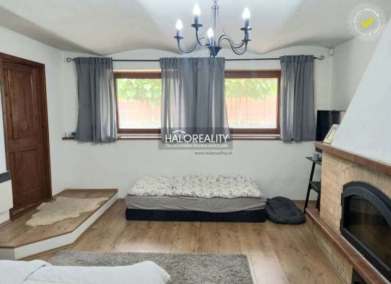 Interior of a family house with a fireplace, bed, and curtains on the windows.