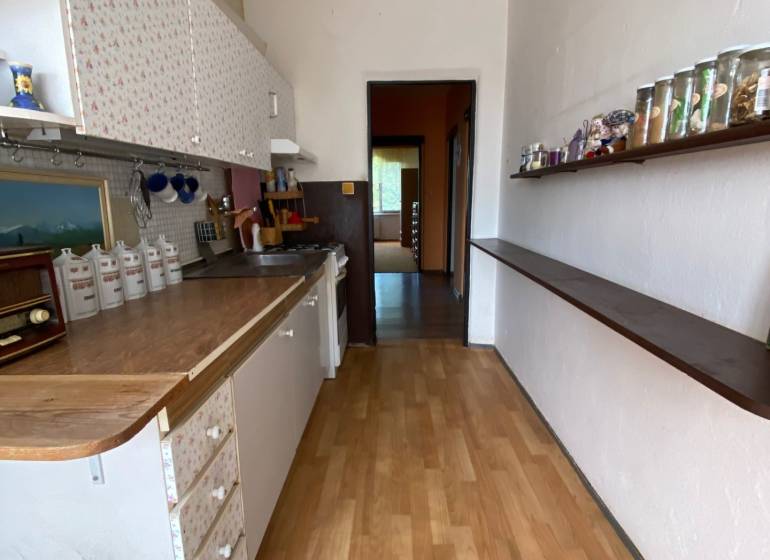 A kitchen in a 4-room apartment with patterned cabinets and a shelf with glasses.