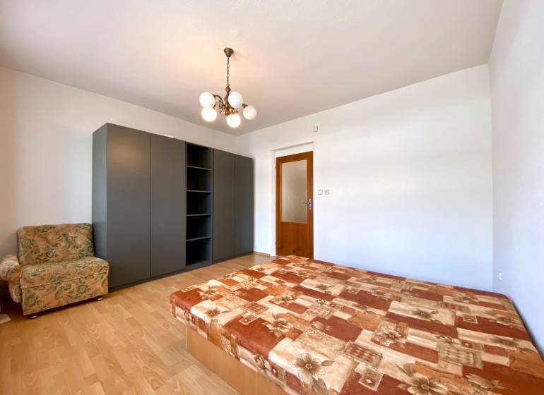 Bedroom in a 2-room apartment with a bed, wardrobe, and armchair.