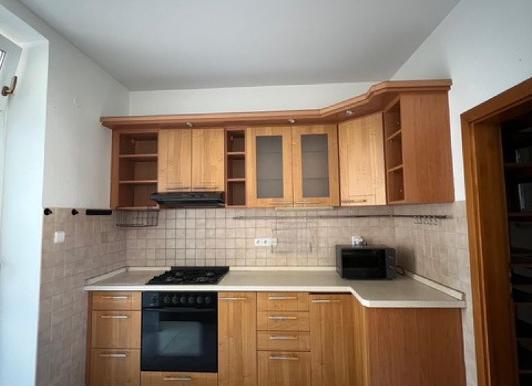 A kitchen in a 5 or more room apartment with wooden cabinets and appliances, tiled floor.