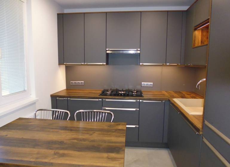 A kitchen with dark cabinets and a wooden countertop in a 3-room apartment.