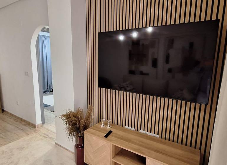 A stylish interior of a 3-room apartment with a TV on a wooden wall.