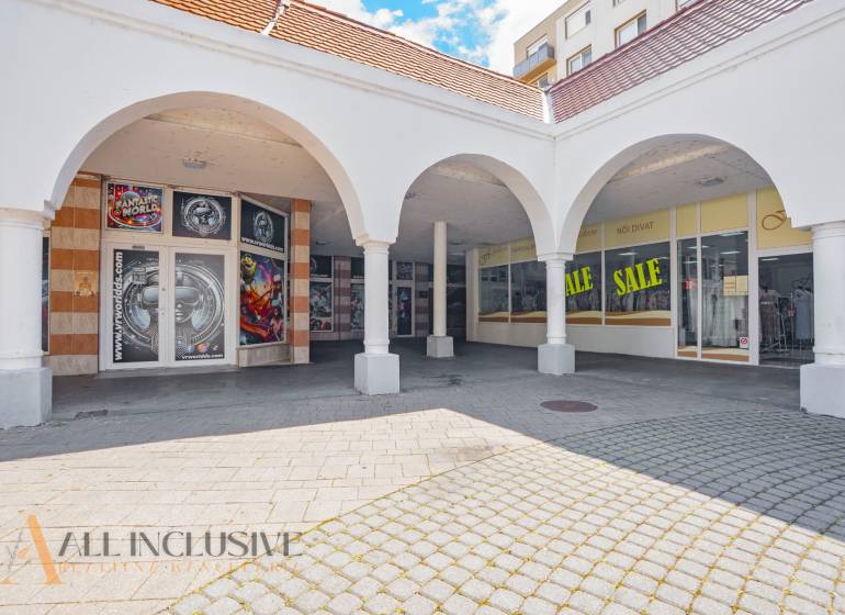 Commercial spaces in Dunajská Streda with arched arcades and advertising for discounts.