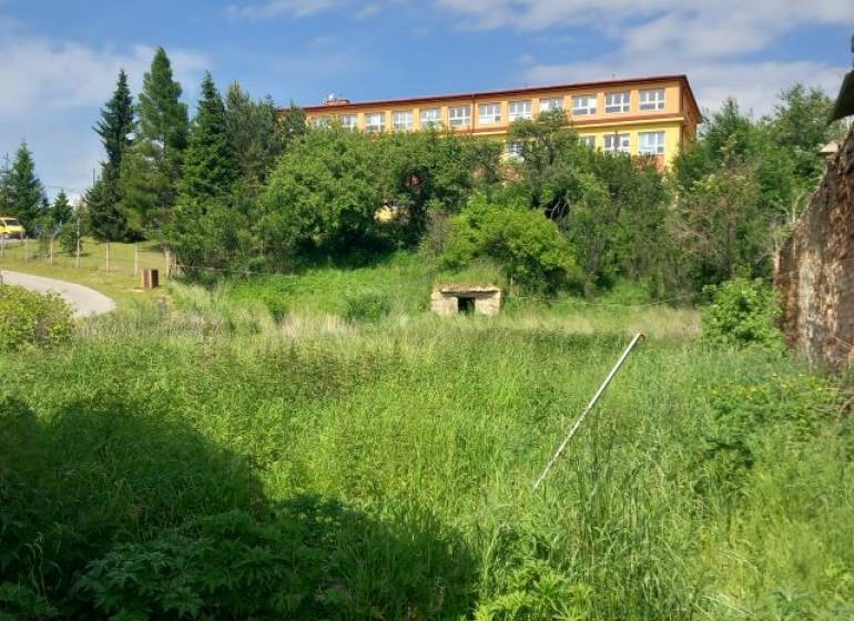 Greenery and building in the background in Pozemky - bývanie, Ľubotín. Serene environment for living.